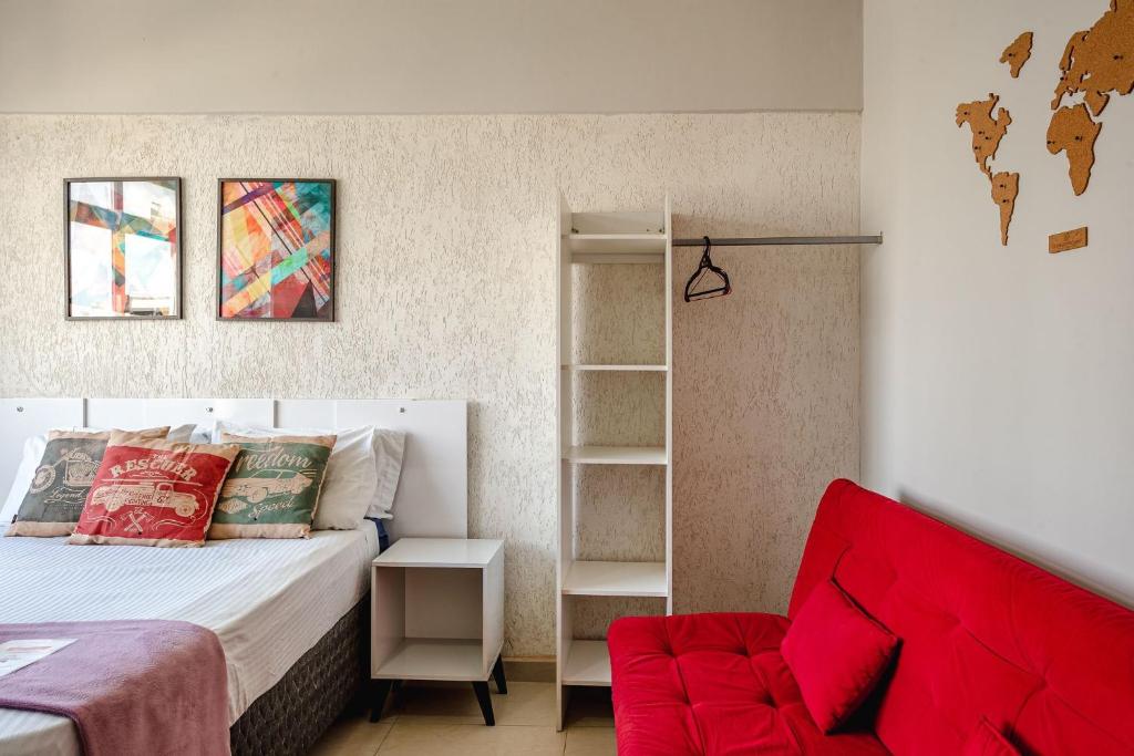 聖保羅的住宿－Pôr do sol 17º andar com vista da cidade，一间卧室配有一张床和一张红色的沙发