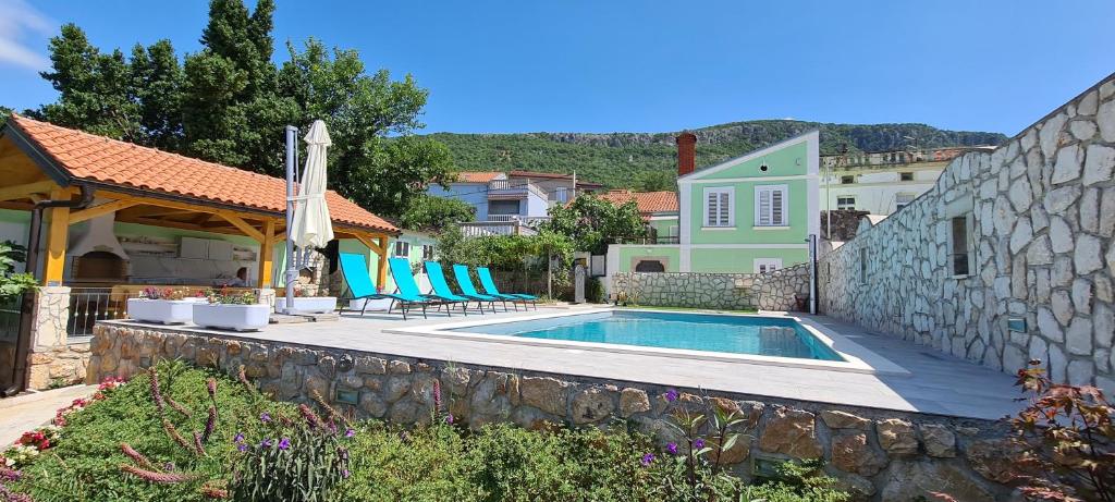 uma casa com piscina e uma parede de pedra em Holiday home Green Point em Grižane