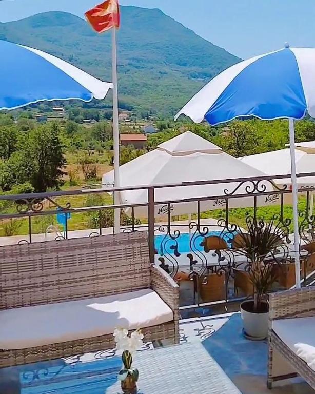 a balcony with benches and umbrellas with a view of a mountain at Apartmani Dumezic in Bar