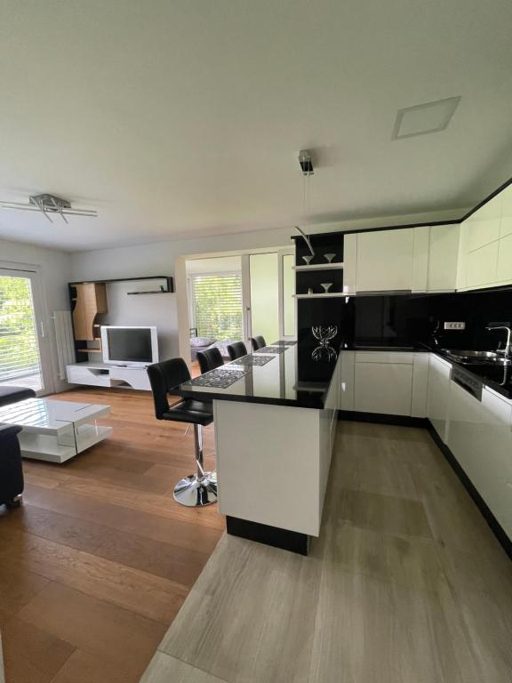 a kitchen with black and white cabinets and a living room at Schöne Gartenwohnung mit Carport und Terrasse! in Graz