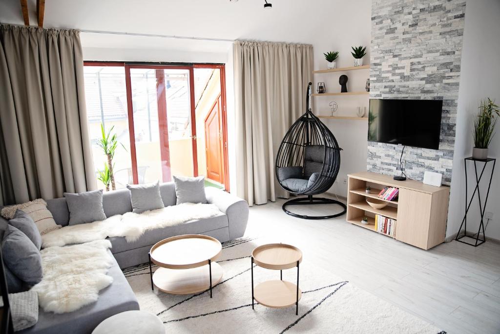 a living room with a couch and chairs and a tv at Cozy modern apartment in the Old Town - Hlavna street in Košice