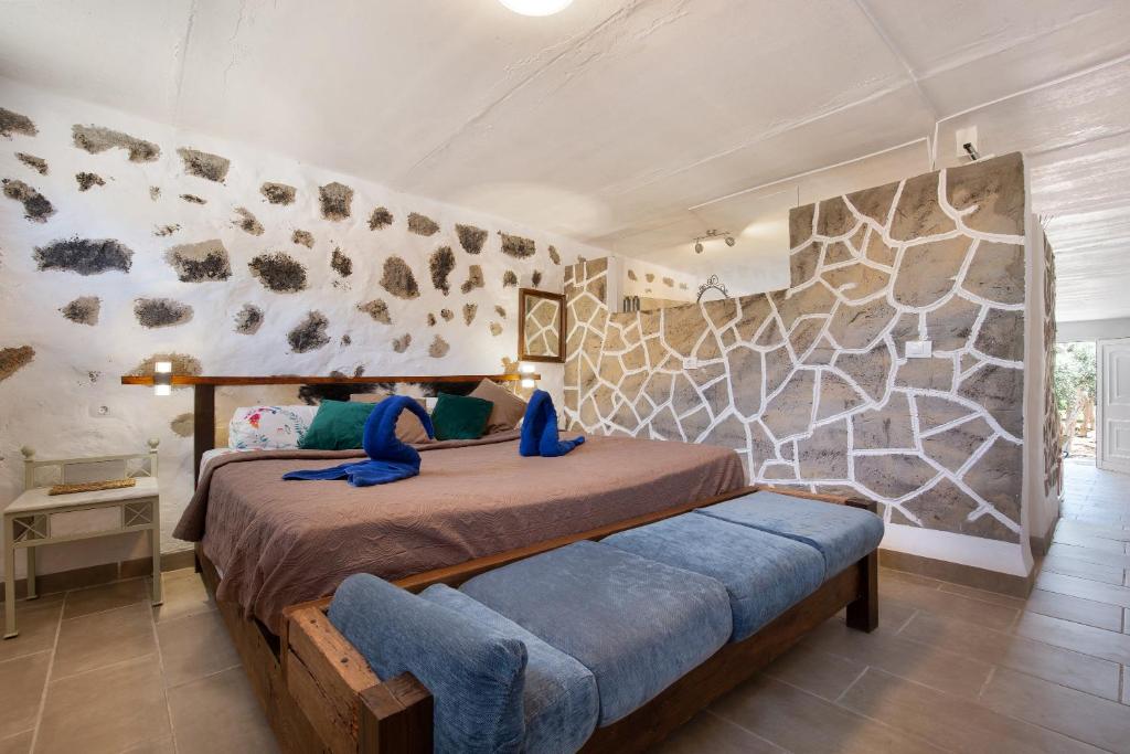 Un dormitorio con una cama y una pared de piedra. en Esencia Eco-rústico, en El Charco