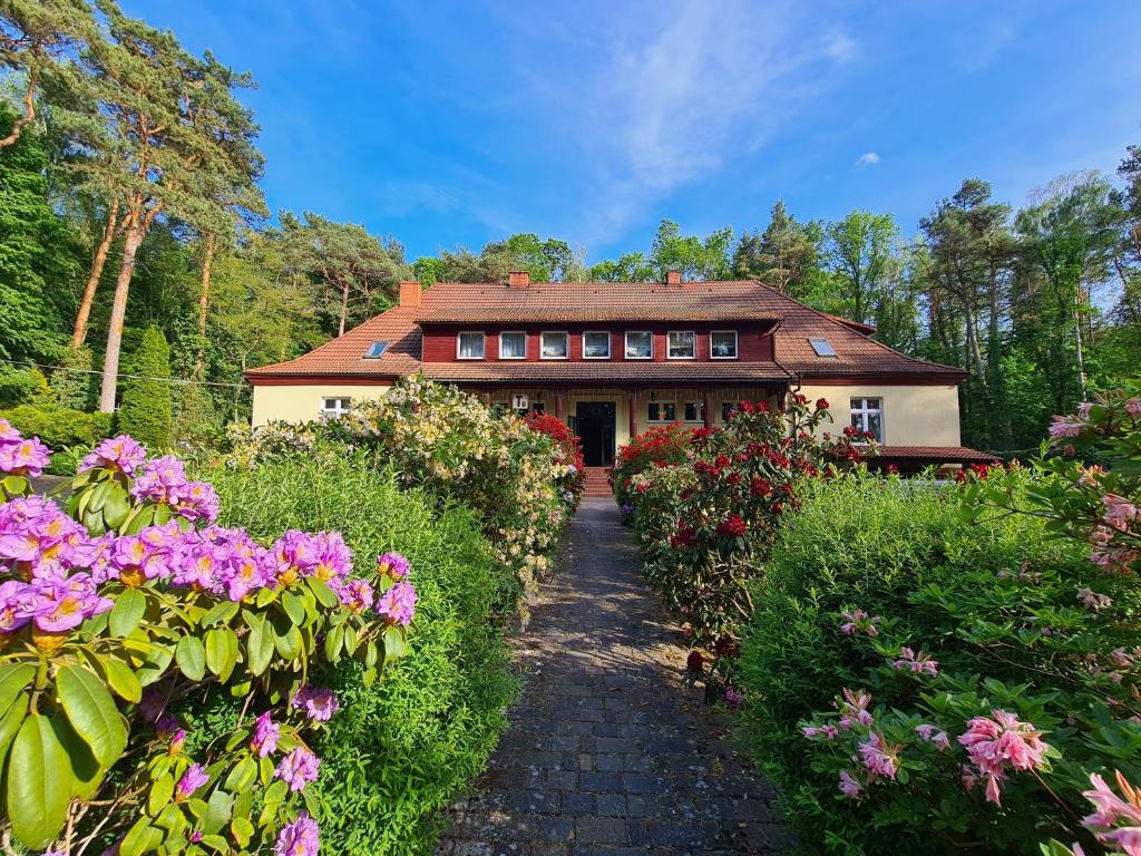 una casa con un camino que conduce a ella con flores en Pasjonat Tu, en Tuczno