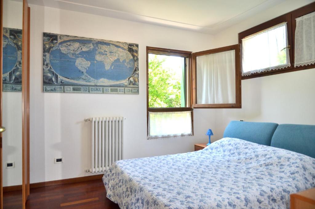 una camera con un letto blu e due finestre di ALLA POSTA cozy apartment close to Venice a Noale