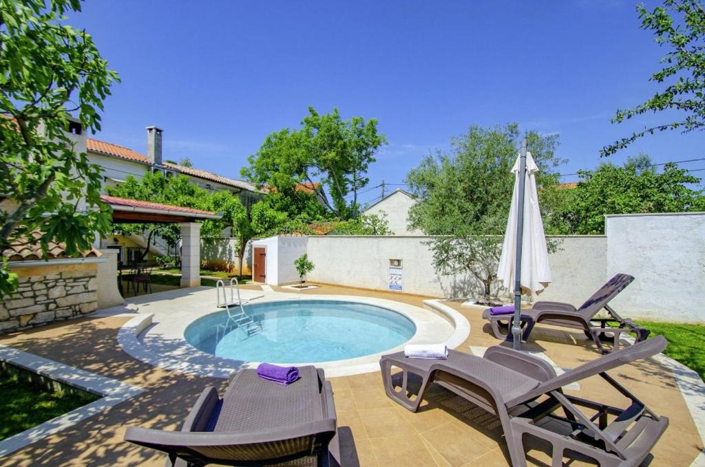 - une piscine avec des chaises et un parasol dans l'établissement Villa Rosana in Muntić - Haus für 4-5 Personen, à Pula