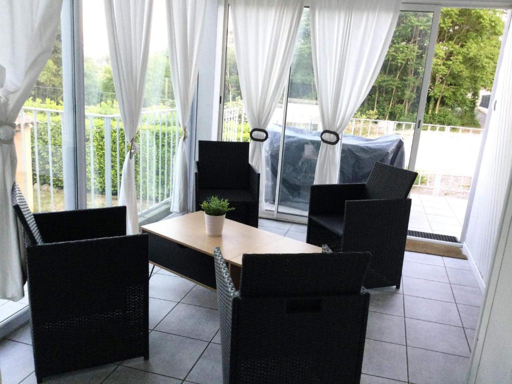 uma sala de jantar com mesa, cadeiras e janelas em les lauriers roses em Aubenas