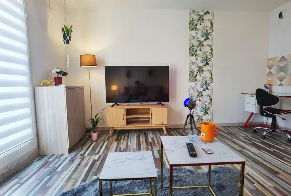 a living room with a flat screen tv and a table at Cosy T1bis proche CentreVille, Petit Port, Audencia in Nantes