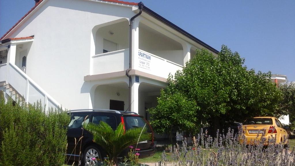 a car parked in front of a white house at Holiday S&M in Lopar