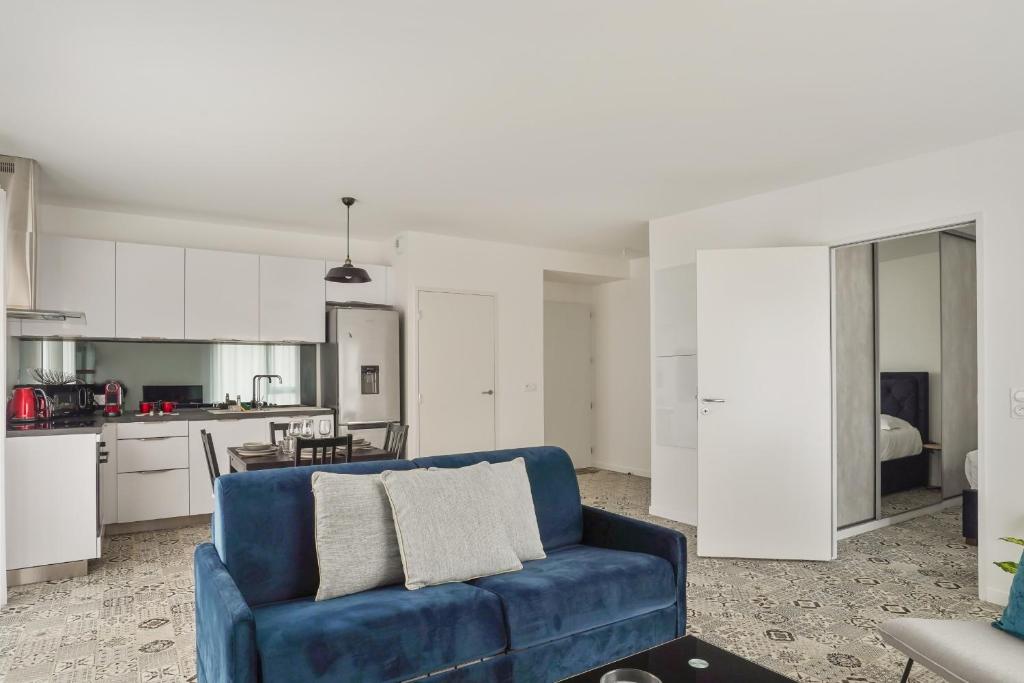 uma sala de estar com um sofá azul e uma cozinha em Appartement des Tours - Welkeys em La Rochelle