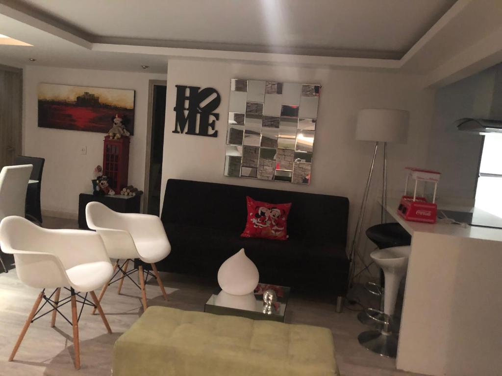 salon z czarną kanapą i białymi krzesłami w obiekcie Habitación Deluxe w mieście Bogota