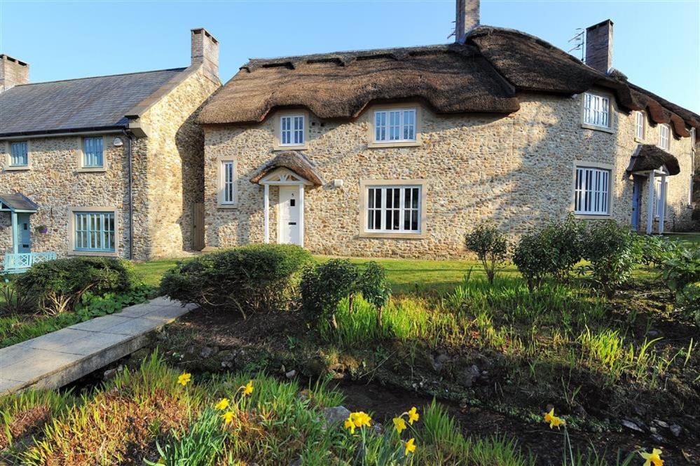 duży kamienny dom z dachem krytym strzechą w obiekcie Springhill Cottage w mieście Lyme Regis