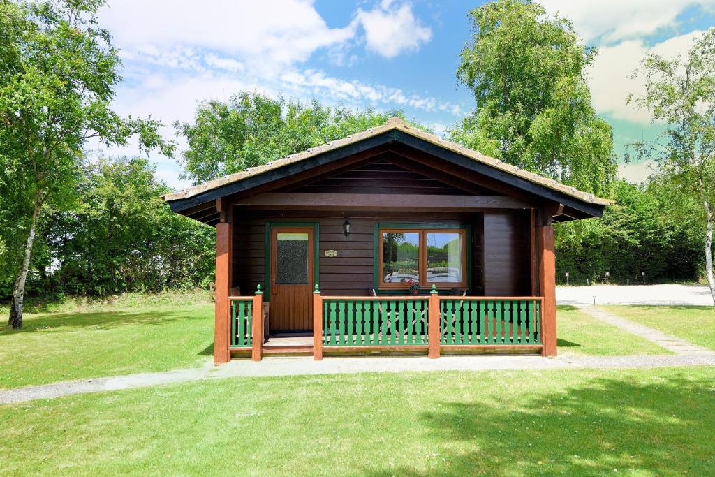 a small cabin with a porch in a park at 4 Pinewood Retreat in Lyme Regis