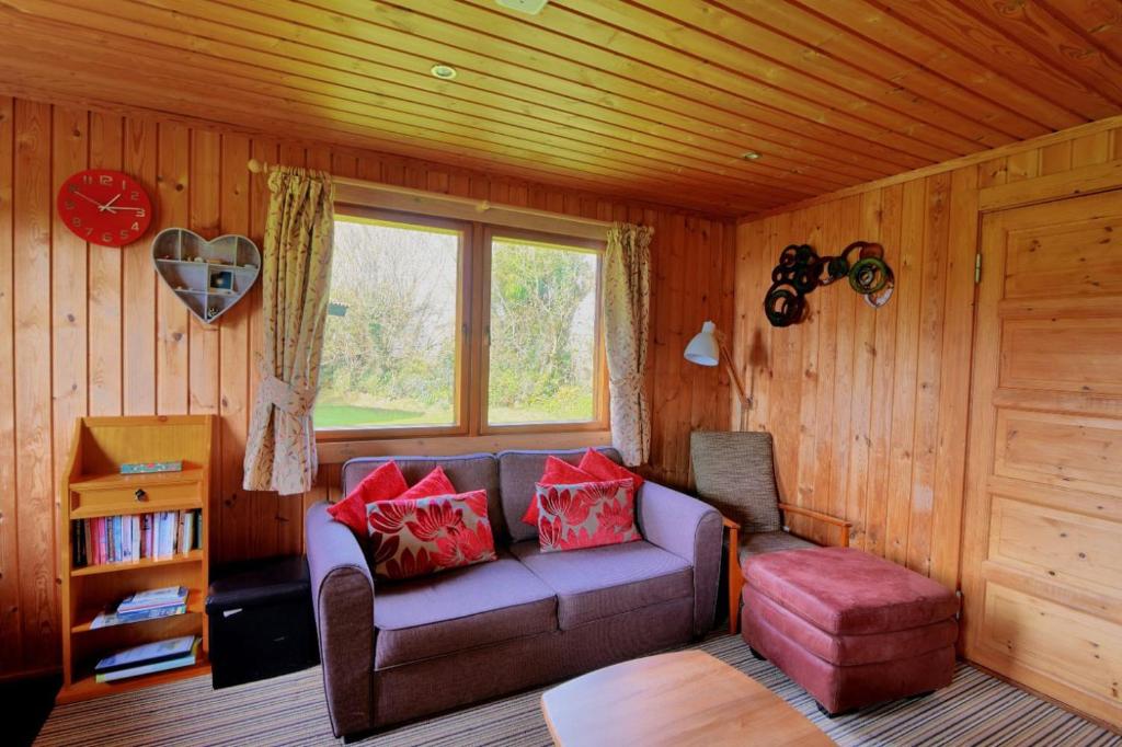 a living room with a couch and a window at 10 Pinewood Retreat in Lyme Regis
