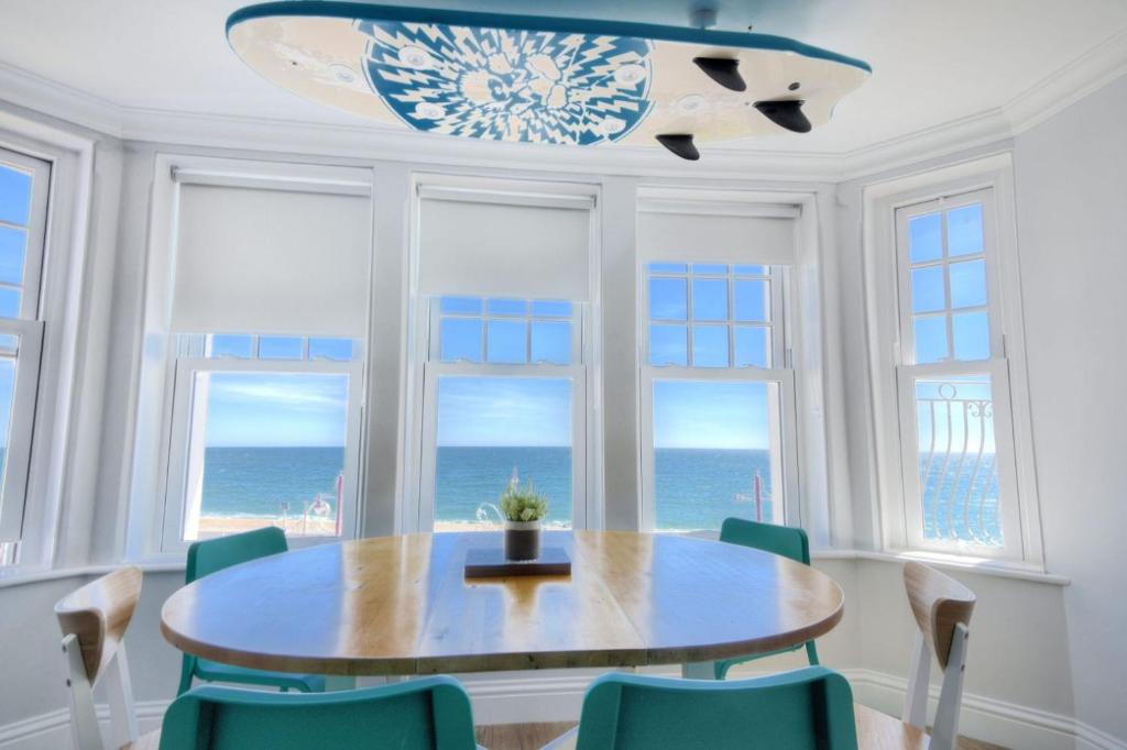 uma sala de jantar com mesa e cadeiras e o oceano em Breakwater em Seaton