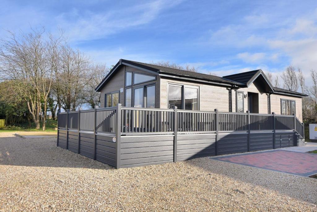 a house with a fence in front of it at Hazelwood 4 Pinewood Retreat in Lyme Regis