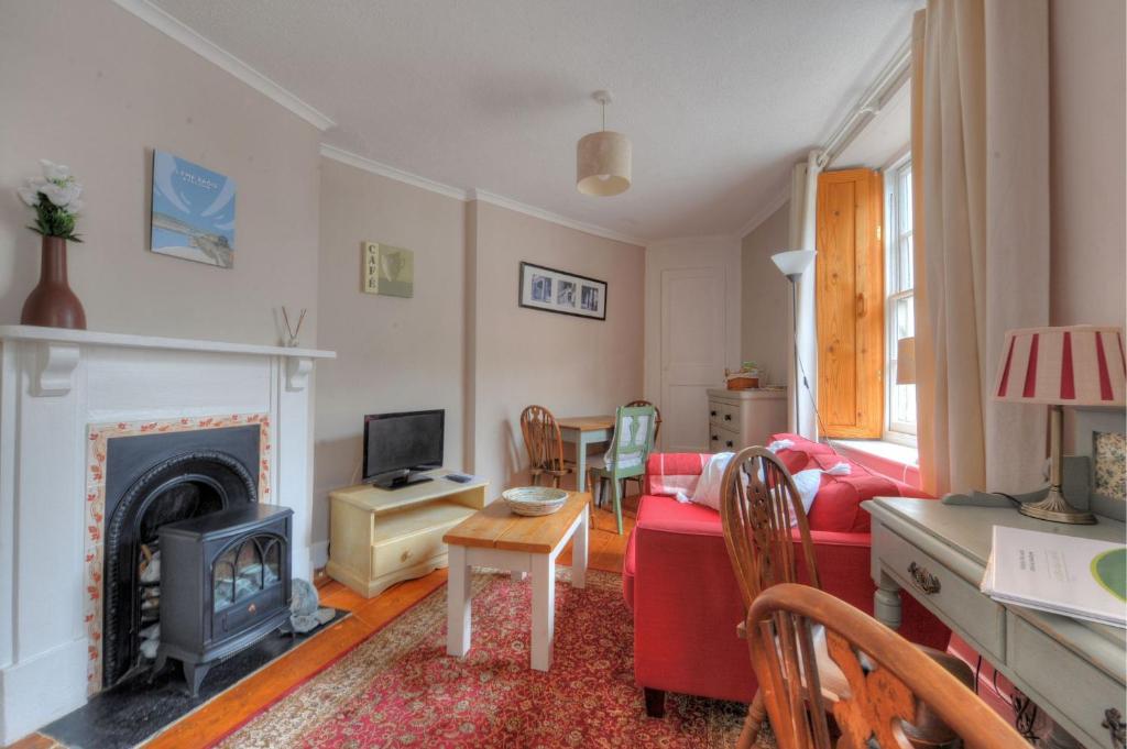 Una sala de estar con un sofá rojo y una chimenea. en Driftwood, en Lyme Regis