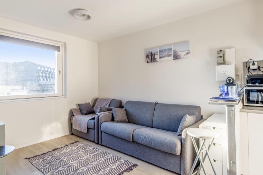 - un salon avec un canapé bleu et une fenêtre dans l'établissement Beau studio avec vue mer dans le port de Deauville - Welkeys, à Deauville