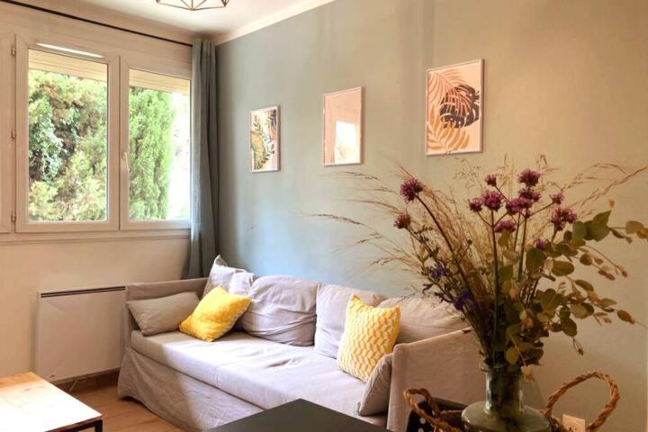 - un salon avec un canapé et un vase fleuri dans l'établissement Appartement calme et ensoleillé Montpellier, à Montpellier
