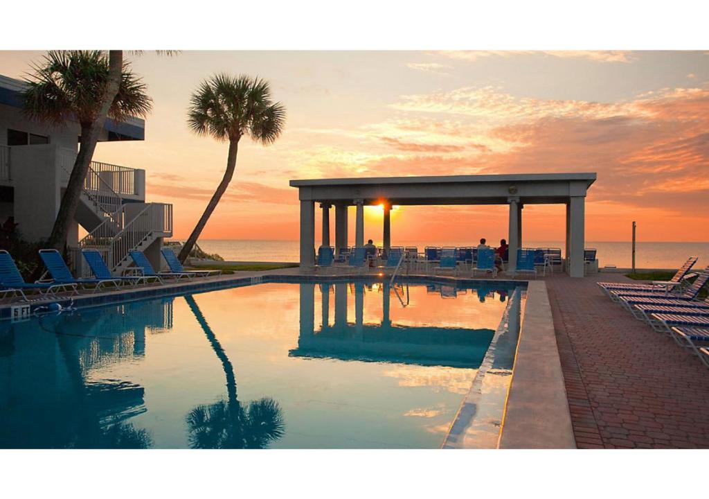 a swimming pool with a view of the ocean at sunset at Via Roma Beach Resort in Bradenton Beach