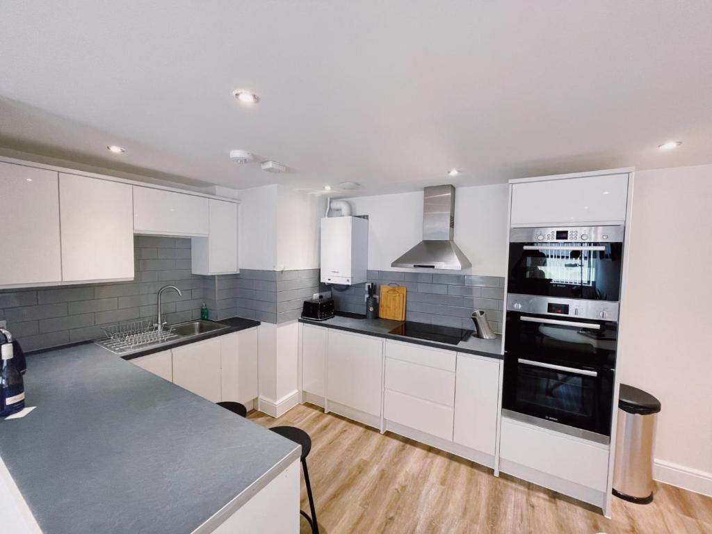 uma cozinha com armários brancos e uma bancada em Prosper House Apartment 2 em Norwich