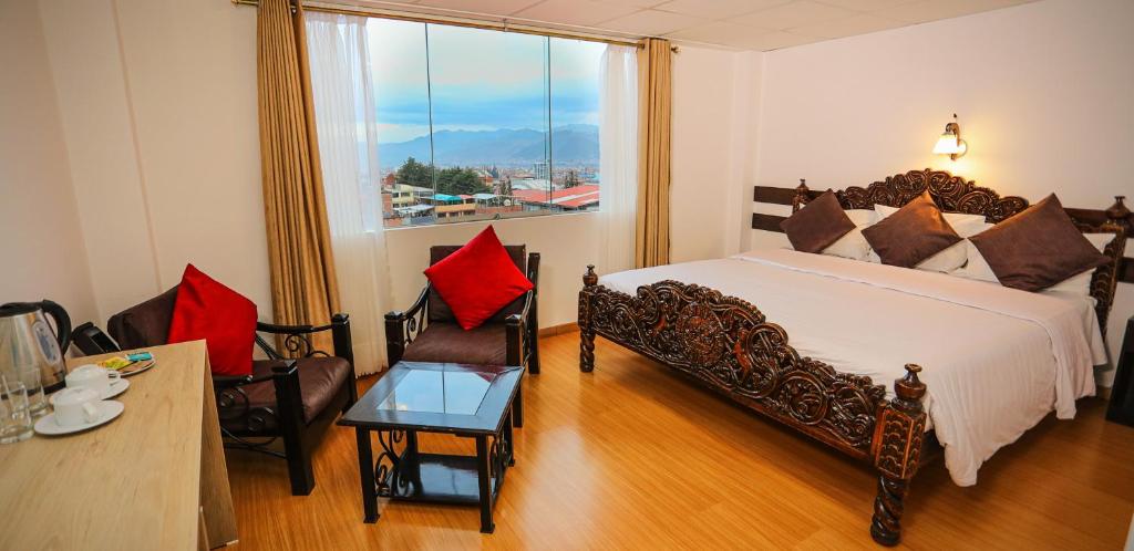 Hotel Kapac Inn-San Blas في كوسكو: غرفة نوم بسرير وطاولة ونافذة