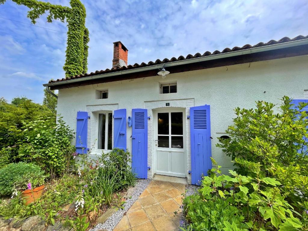 ein weißes Haus mit blauen Fensterläden in der Unterkunft Champs Chevrier in Mézières-sur-Issoire