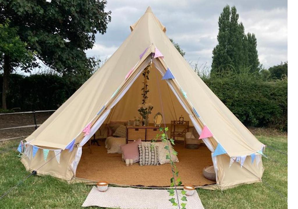 a white tent with a bed in a yard at Southfields Bell Tent. in Egmanton