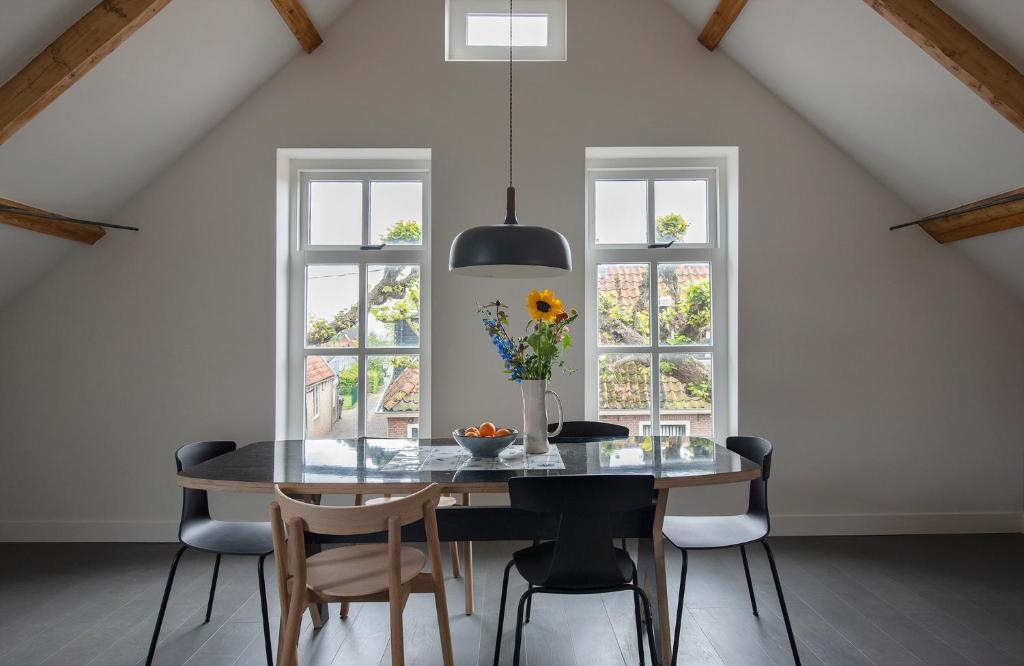 uma sala de jantar com mesa, cadeiras e janelas em Schitterend appartement in dorpsstraat Langweer! em Langweer