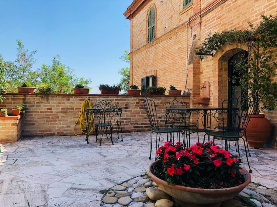 un patio con mesa, sillas y flores en Casa Rosy nel centro del borgo di Patrignone, en Patrignone