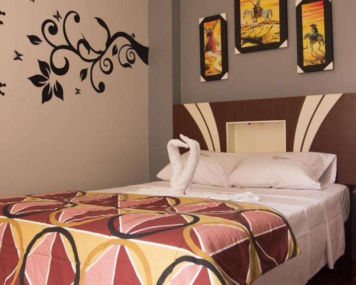 a bedroom with a bed with a painting on the wall at Hostal Las Fresas Lima Airport in Lima