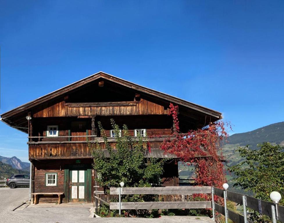 ein großes Holzhaus mit einem Zaun davor in der Unterkunft Berghaus Wiesegg - uriges Tiroler Bauernhaus in Fügenberg