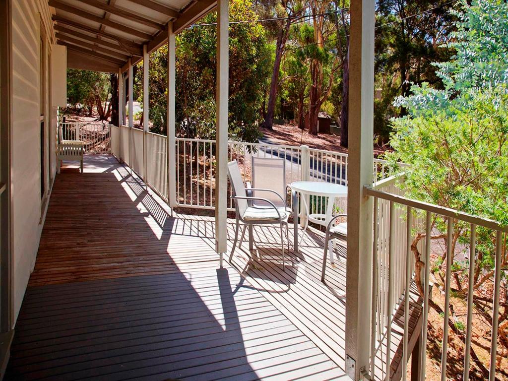 a patio area with chairs, tables, and umbrellas at Noonameena Cottage in Halls Gap