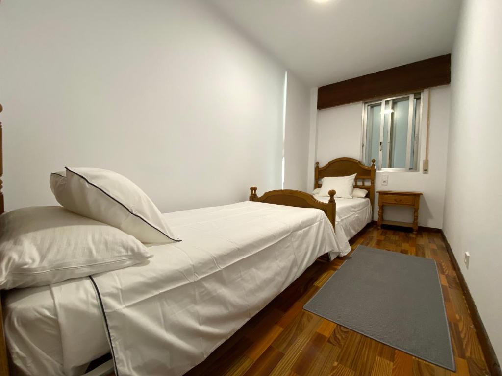 um quarto branco com 2 camas e uma janela em Playa Compostela em Vilagarcía de Arousa