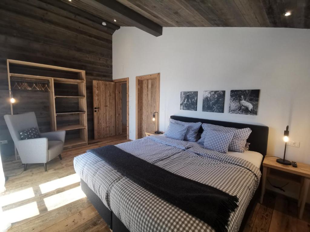 a bedroom with a large bed and a chair at Kräuterhof Chalets in Missen-Wilhams