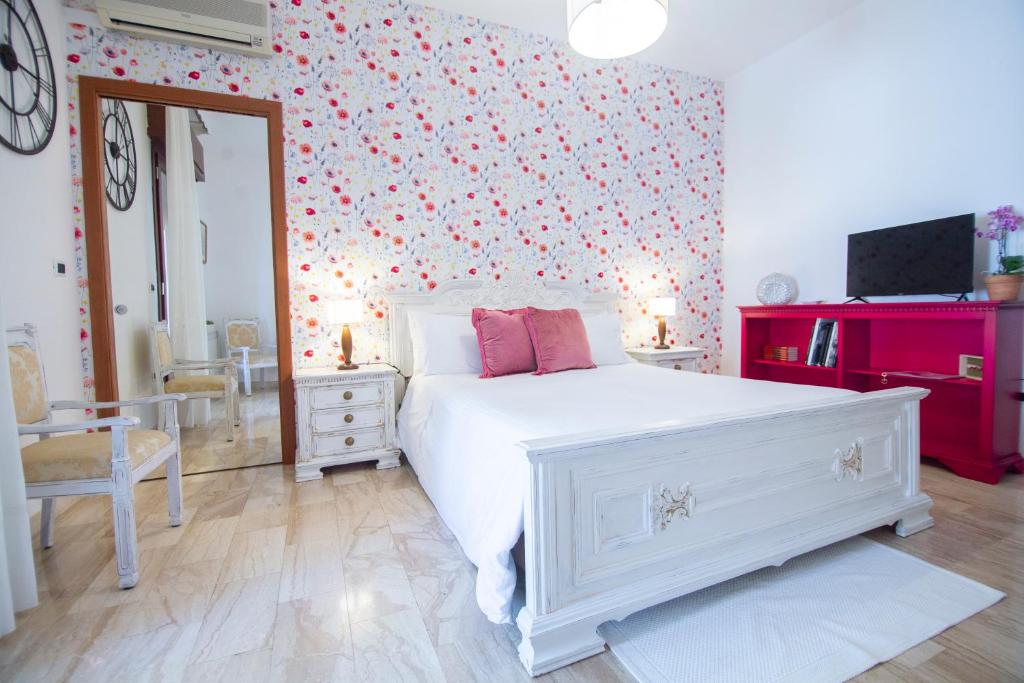 um quarto com uma cama branca e uma parede floral em B&B Calamoresca em Àrbatax