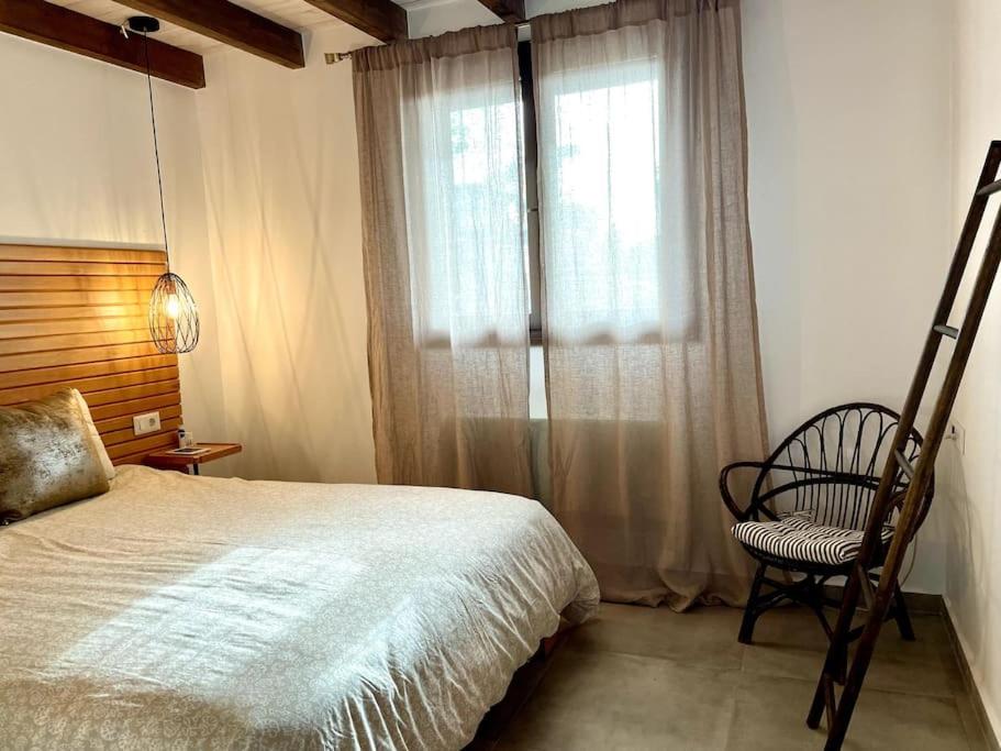 a bedroom with a bed and a chair and a window at Katikies Savrani in Perivólia