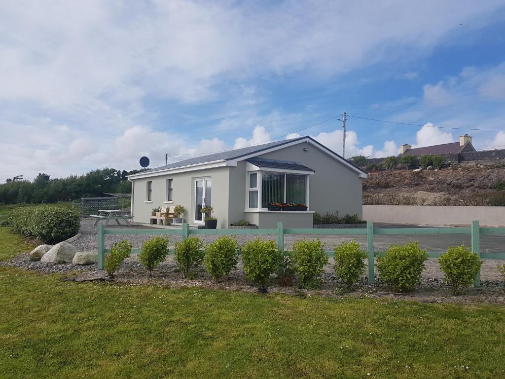 a small white house with a fence in front of it at Sea breeze Cottage in Dungloe