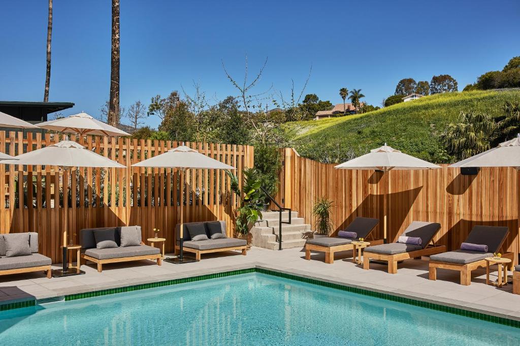a pool with chairs and umbrellas next to a fence at Hotel June Malibu in Malibu
