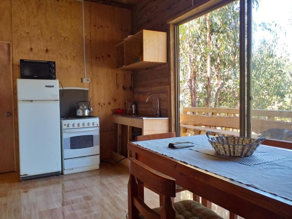 a kitchen with a refrigerator and a table in a cabin at Estancia Don Domingo in Curicó