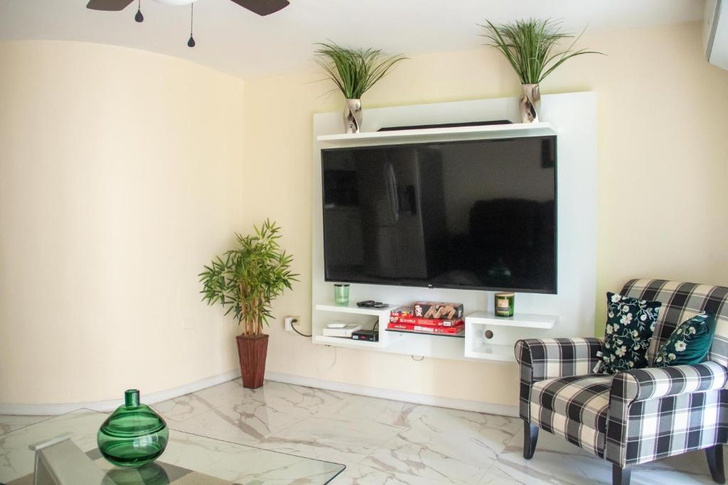 uma sala de estar com televisão e duas cadeiras em C'DaView Apartment Suite em Montego Bay
