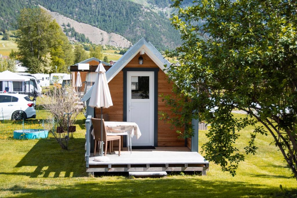 une petite cabine avec une table et un parasol dans l'établissement Camping Muglin, à Müstair