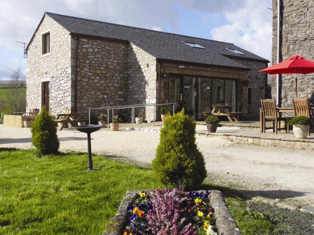 a stone building with a table and an umbrella at Clerk Laithe Lodge in Newton