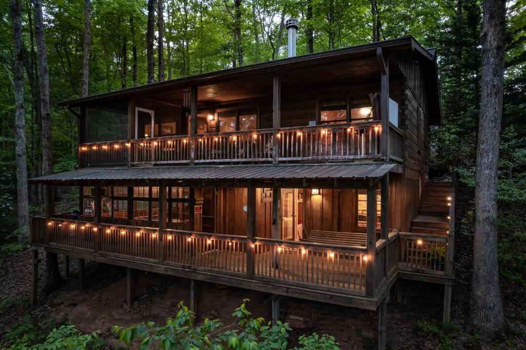 Una casa en el bosque con luces encendidas. en Secluded Sunrise Ridge-10 Min From Blue Ridge, King Beds, Hot Tub, 2 Porches, Fireplace Wood Burning, Mountain View, Cozy, en Blue Ridge