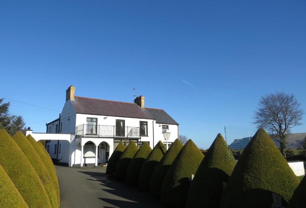 a white house with a row of hedges in front of it at Glendale Bed and Breakfast, Cushendall in Cushendall