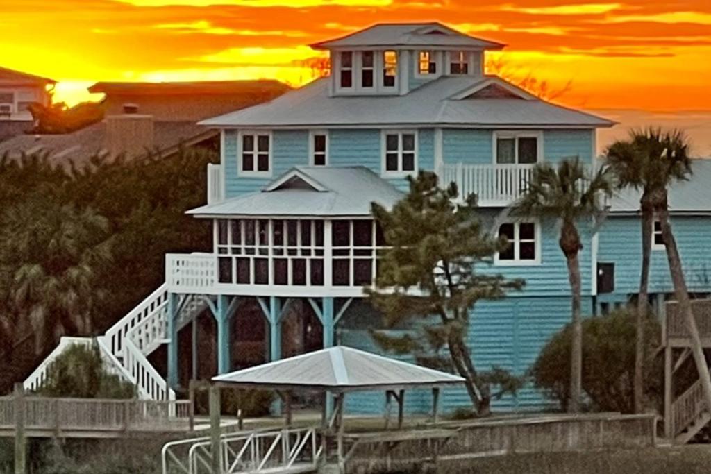 una gran casa en la playa con una puesta de sol en el fondo en The Blue Pelican, en Edisto Beach
