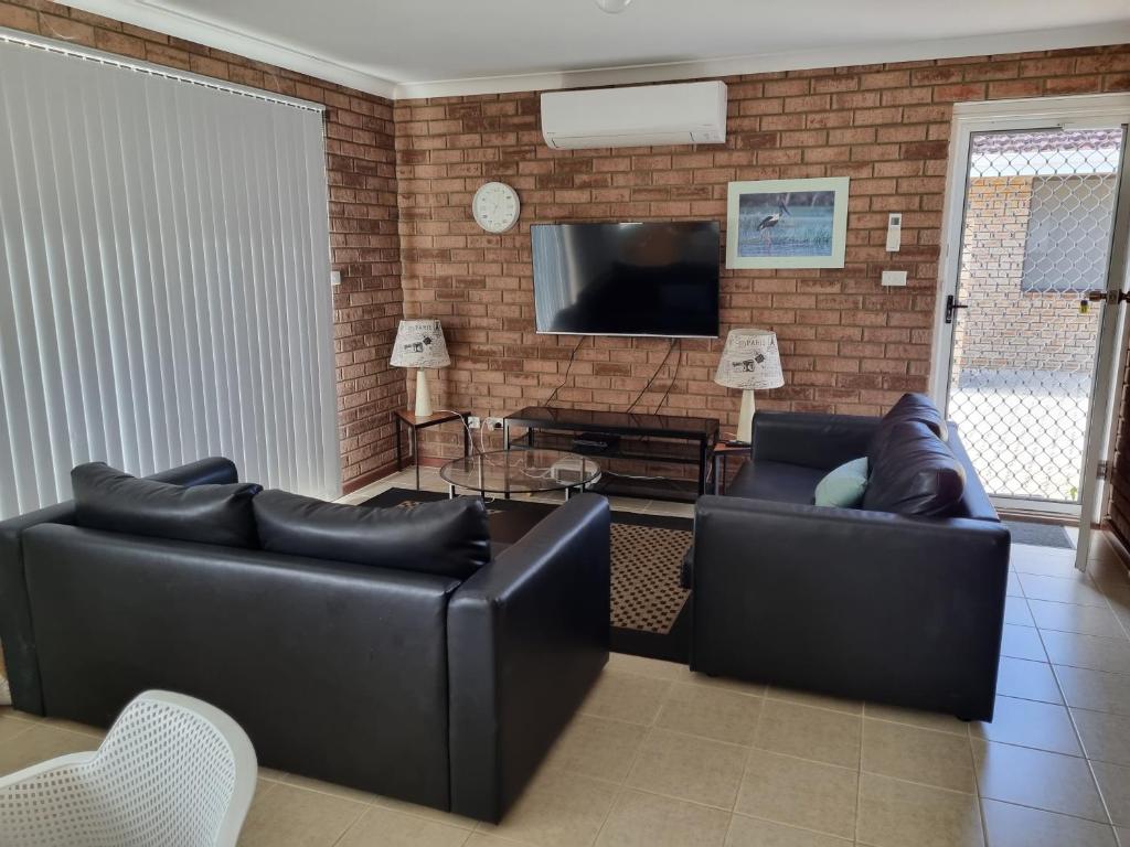 sala de estar con 2 sofás de cuero y TV en Ocean Beach Chalet 16, en Jurien Bay