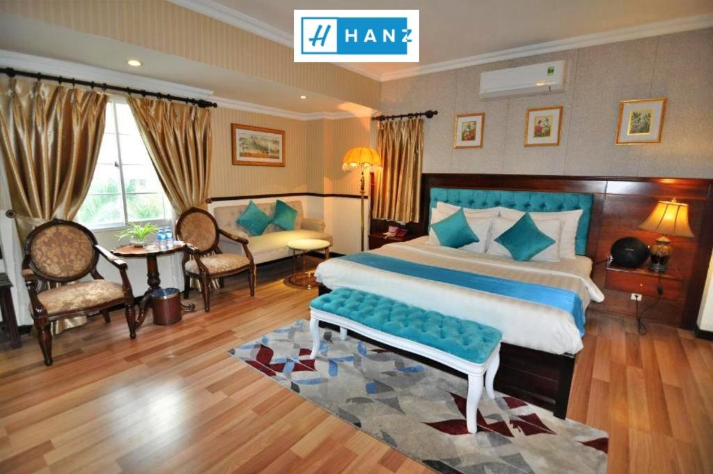 a bedroom with a large bed and a living room at HANZ Vuon Saigon Hotel & Spa in Ho Chi Minh City