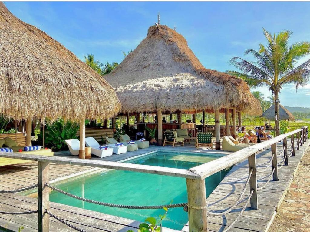 a resort with a swimming pool and thatched umbrellas at Sumba Beach House in Waikabubak