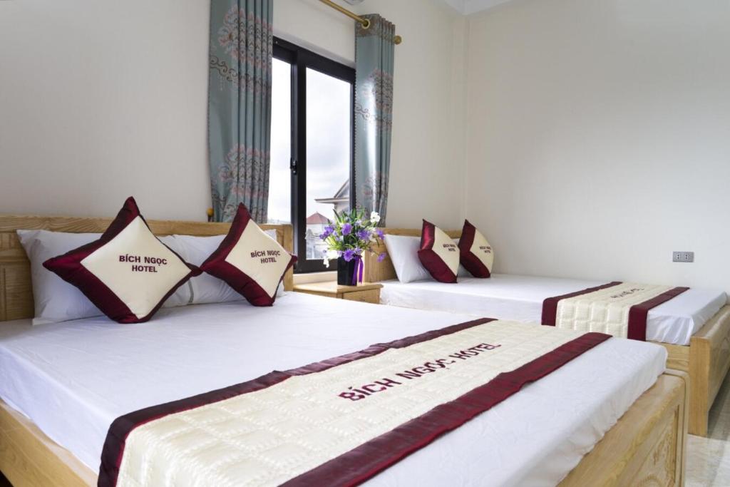 two beds in a room with windows at Bích Ngọc Hotel Quan Lạn - Thứ 7 nhận 5 phòng trở lên in Làng Liễu