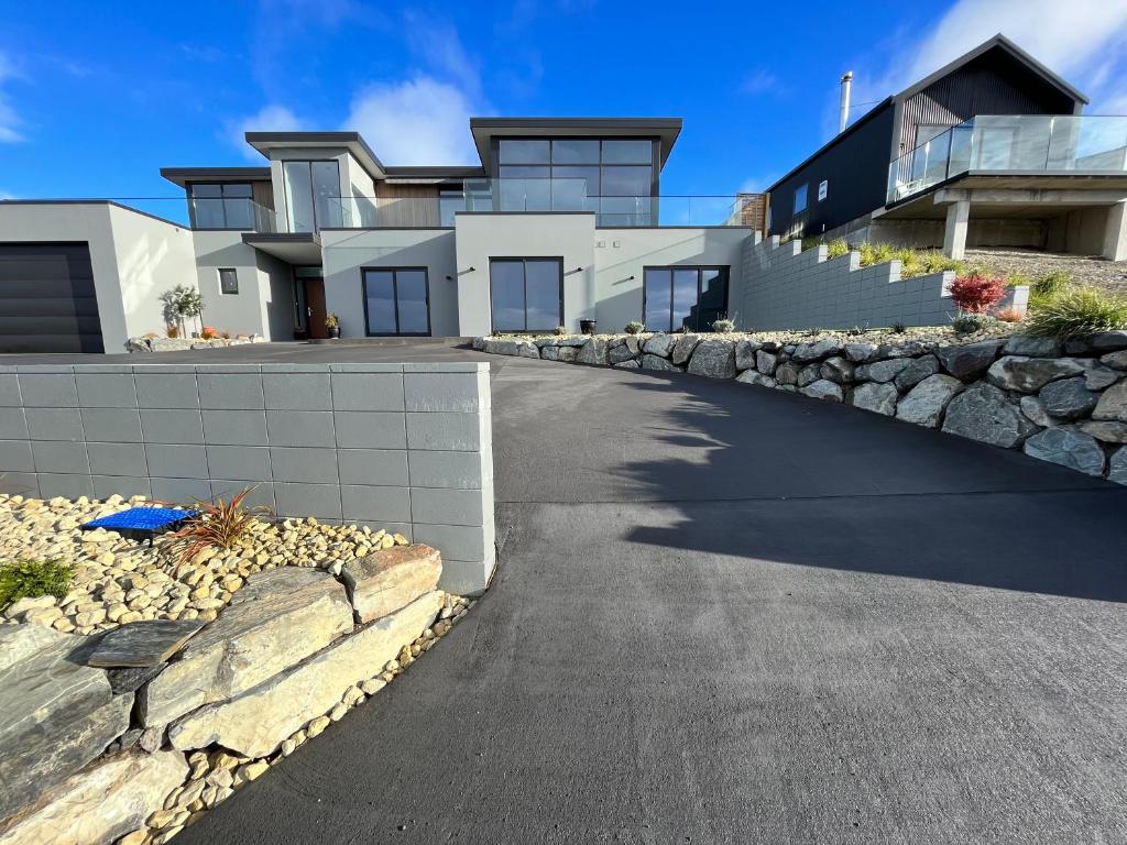 a house with a stone wall and a driveway at Starry Vista-Alpha in Lake Tekapo